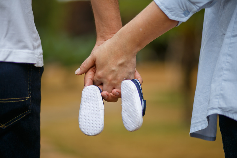 Parents Hands Holding Baby Shoes